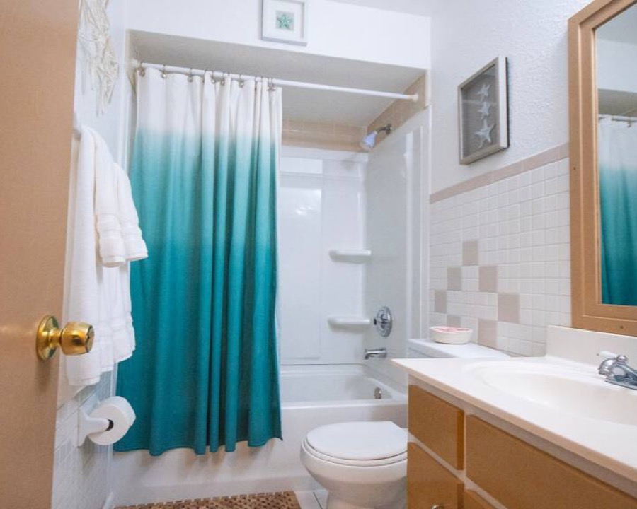 Folded white towels on a rail beside a tiled shower and vanity
