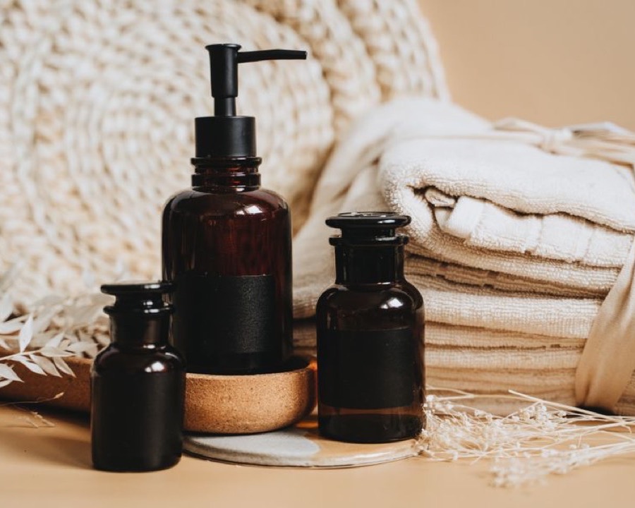 Amber apothecary bottles beside folded cream towels