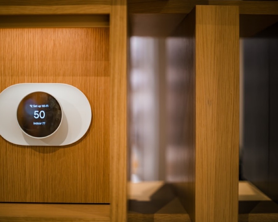 A smart thermostat mounted on warm oak panelling