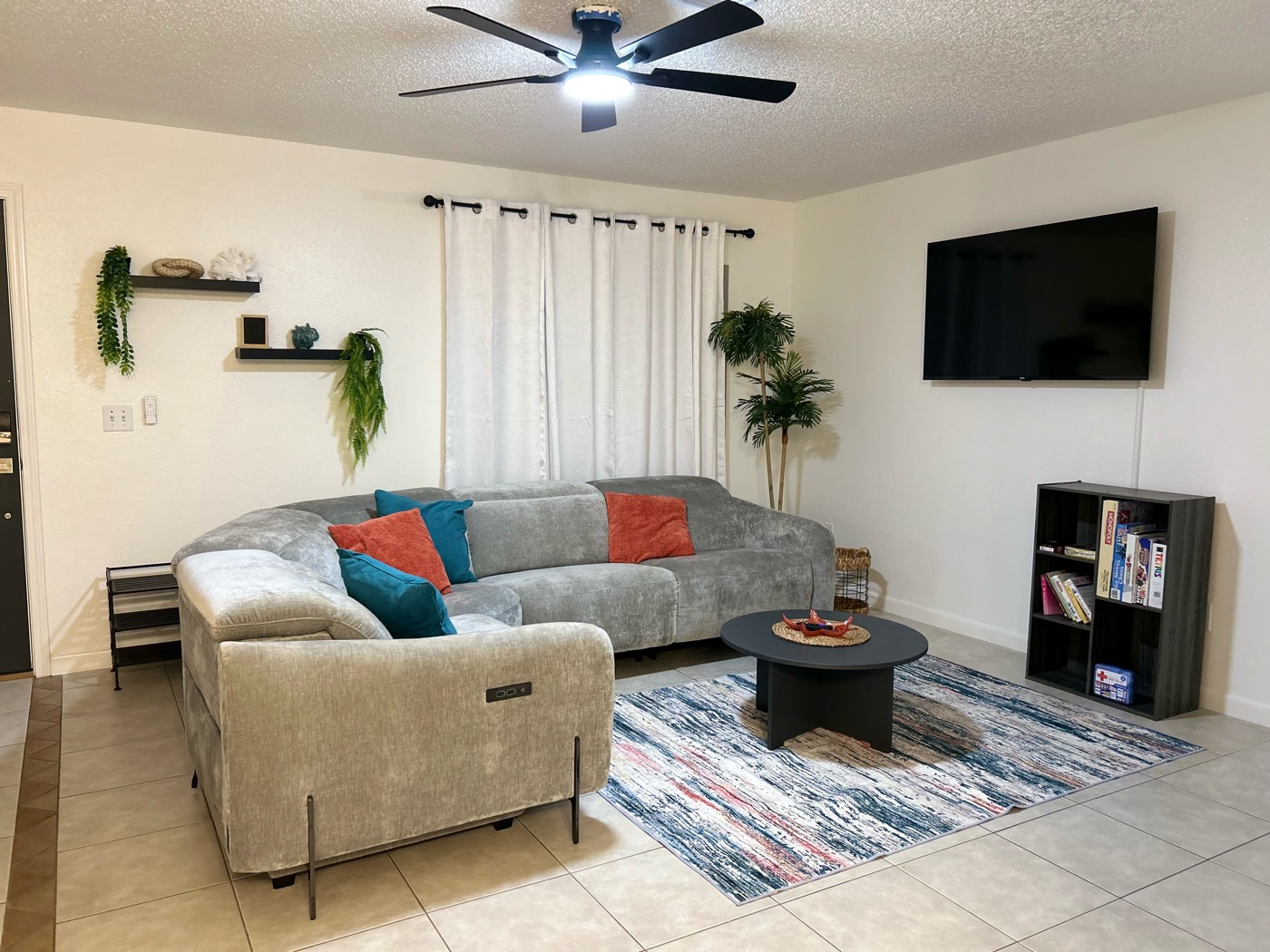 Moongate Meadows living room with a grey sectional, ceiling fan and tile floors